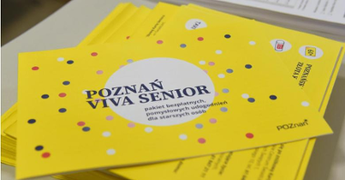 Zdjęcie przedstawia stos materiałów informacyjnych. Ich okładka to żółta kartka w kolorowe kropki, na niej białe koło i napis: Poznań Viva Senior