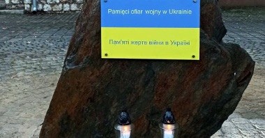 Na zdjęciu ciemny kamień, na nim tabliczka z napisem w dwóch językach: pamięci ofiarom wojny w Ukrainie