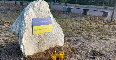 Na zdjęciu biały kamień, na nim tabliczka z napisem w dwóch językach: pamięci ofiar wojny w Ukrainie