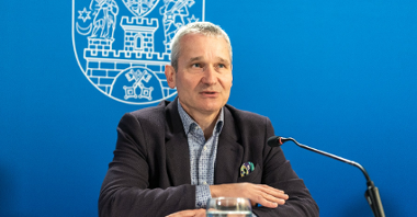 Na zdjęciu Jędrzej Solarski, zastępca prezydenta Poznania, przy mikrofonie, za nim granatowa ścianka z rysunkiem herbu miasta