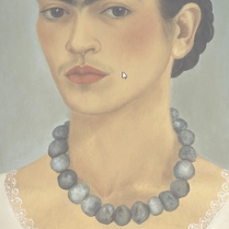 kobieta w związanych w kok ciemnych włosach. Kobieta ma jasną koszulę z koronkowym wykończeniem i naszyjnik z ciemnych korali. Tło jest ciemnoszare.