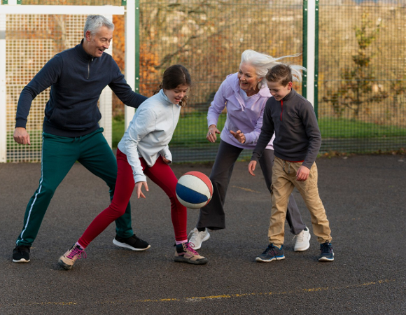 Rodzinna gra w koszykówkę - dwoje starszych osób i dwoje dzieci w trakcie kozłowania piłką