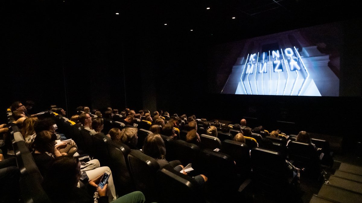 W ciemnej sali kinowej na fotelach siedzą widzowie, na ekranie napis kino muza