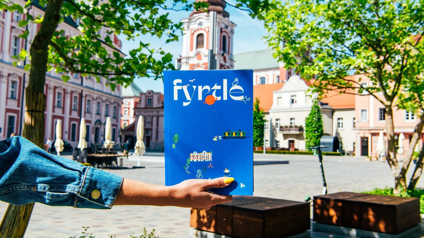 Zdjęcie przedstawia okładkę książki "Fyrtle". W tle plac Kolegiacki.