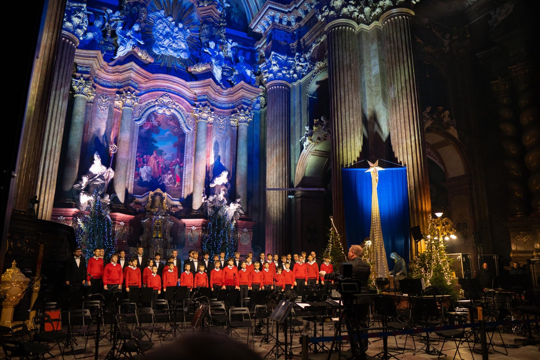 Na zdjęciu chór śpiewający w poznańskiej garze, widać chórzystów, podświetlony ołtarz i dyrygenta