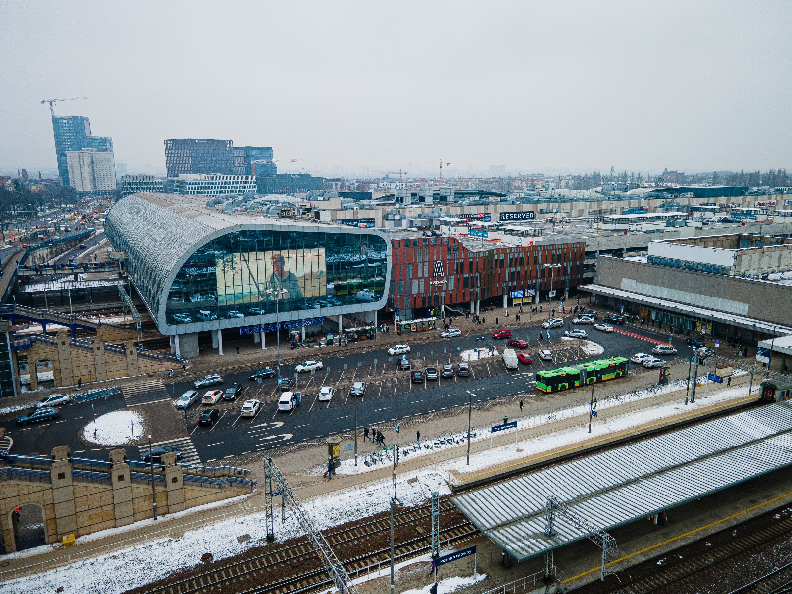 Na zdjeciu kilka osób, niektóre w kamizelkach odblaskowych, stoją przed szopą, w której schronienie ma osoba w kryzysie bezdomności