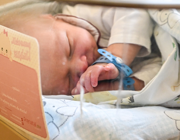 Na zdjęciu niemowlę śpiące w szpitalnym łóżeczku