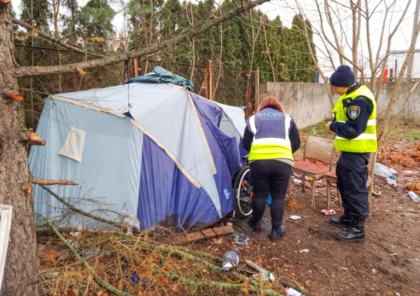 Na zdjęciu pracownica MOPR i strażnik miejski stoją u wejścia do namiotu osoby w kryzysie bezdomności