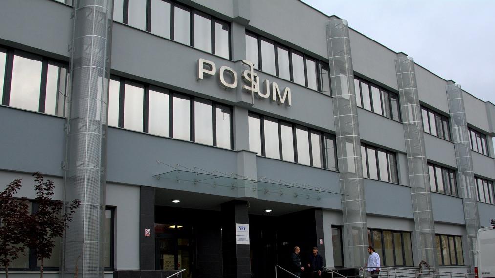 Fasada POSUM: nowoczesna, trzykondygnacyjna, szara, nad głównym wejściem napis "POSUM" - grafika artykułu