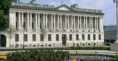 Budynek Biblioteki Raczyńskich: biały gmach z kolumnami, na pierwszym planie kwiaty na placu Wolności