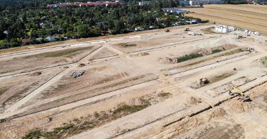 Na zdjęciu znajduje się plac budowy uwieczniony z góry przy pomocy drona. Widać na nim m.in. powstający dom działkowca, a także samochody dostawcze i materiały budowlane