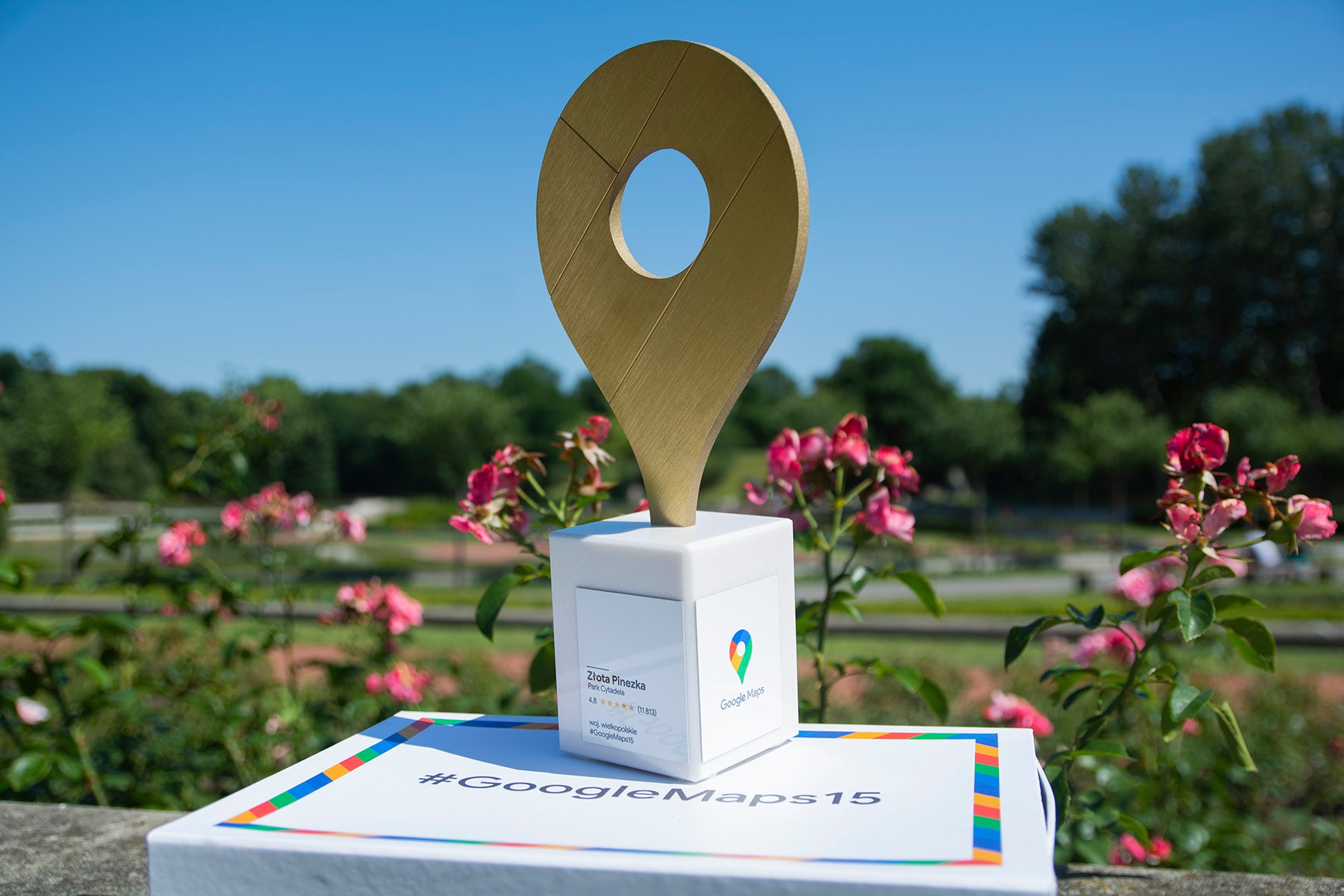Na zdjęciu znajduje się nagroda Google - Złota Pinezka - uwieczniona na tle kwiatów w Parku Cytadela - grafika artykułu