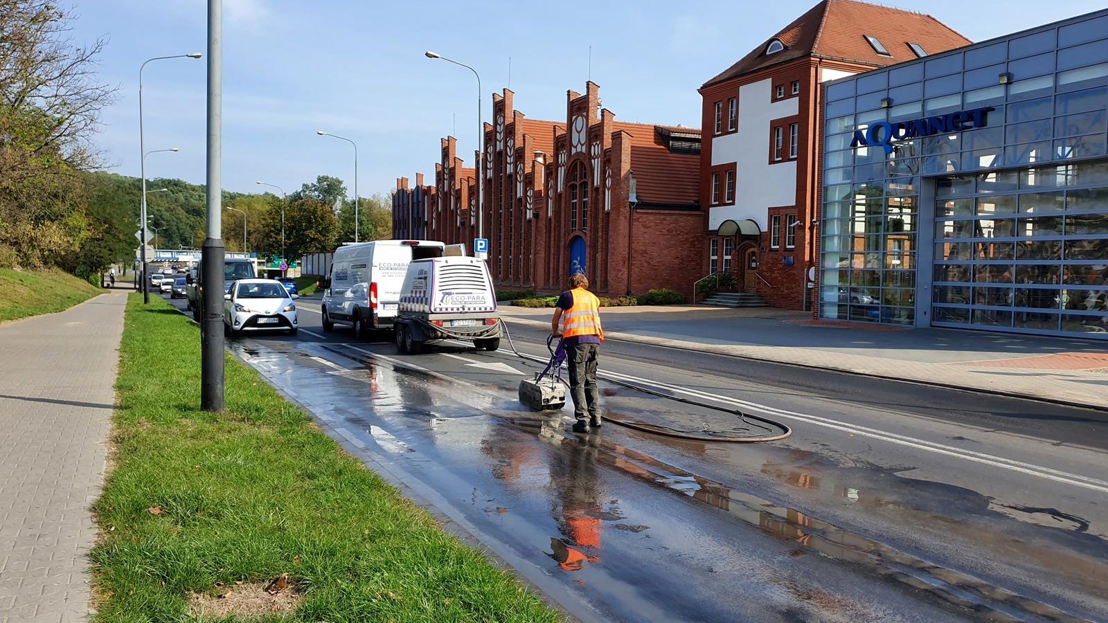 frezowanie ul. Garbary; samochody omijaj robotników; w tle budynki Aquanetu