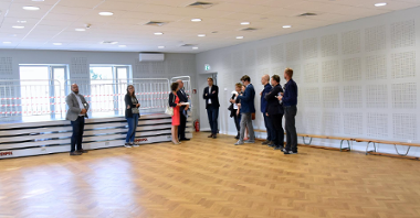 Zdjęcie przedstawia wnętrze sali do ćwiczeń. W pomieszczeniu znajdują się przedstawiciele Miasta Poznania, domu kultury i wykonawcy prac.