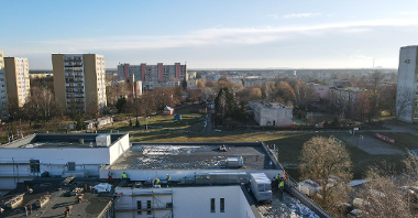 Galeria zdjęć przedstawia salę gimnastyczną, która powstaje przy szkole na osiedlu Sobieskiego. Zdjęcia zrobiono z góry. Wokół widać bloki.