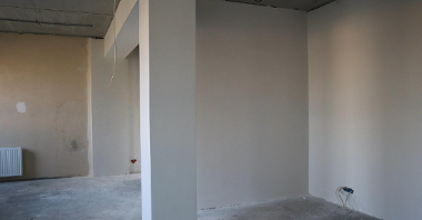 Zdjęcie przedstawia wnętrze sali gimnastycznej. Widać na nim białe ściany i kolumny.