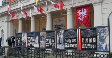 Zdjęcie przedstawia budynek muzeum, na którym wywieszone są flagi polskie oraz powstańcze. Na pierwszym planie znajdują się zdjęcia Ignacego Paderewskiego, prezentowane w ramach wystawy.