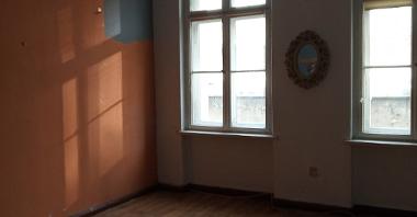 Na zdjęciu pusty pokój do remontu, w centrum dwa duże okna