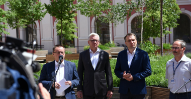Na zdjęciu dziedziniec urzędu miasta, przy mikrofonach stoi czterech mężczyzn, w tym Jacek Jaśkowiak i Mariusz Wiśniewski, w tle drzewa