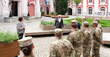Dziedziniec Urzędu Miasta Poznania. W centrum Jacek Jaśkowiak, obok kobieta. Przed nimi, w grupie, stoją żołnierze w mundurach