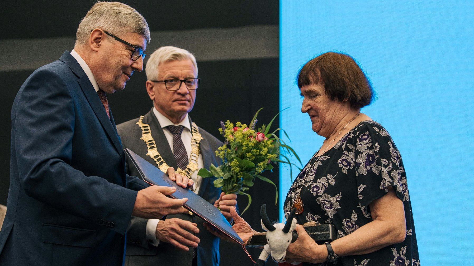 Kobieta odbierająca nagrodę z rąk Grzegorza Ganowicza, za nią Jacek Jaśkowiak trzymający kwiaty - grafika artykułu