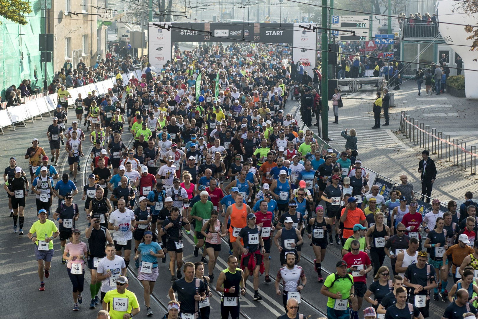 Zdjęcie przedstawia biegaczy podczas Poznańskiego Maratonu. Tłum ludzi biegnie ulicami Poznania. - grafika artykułu