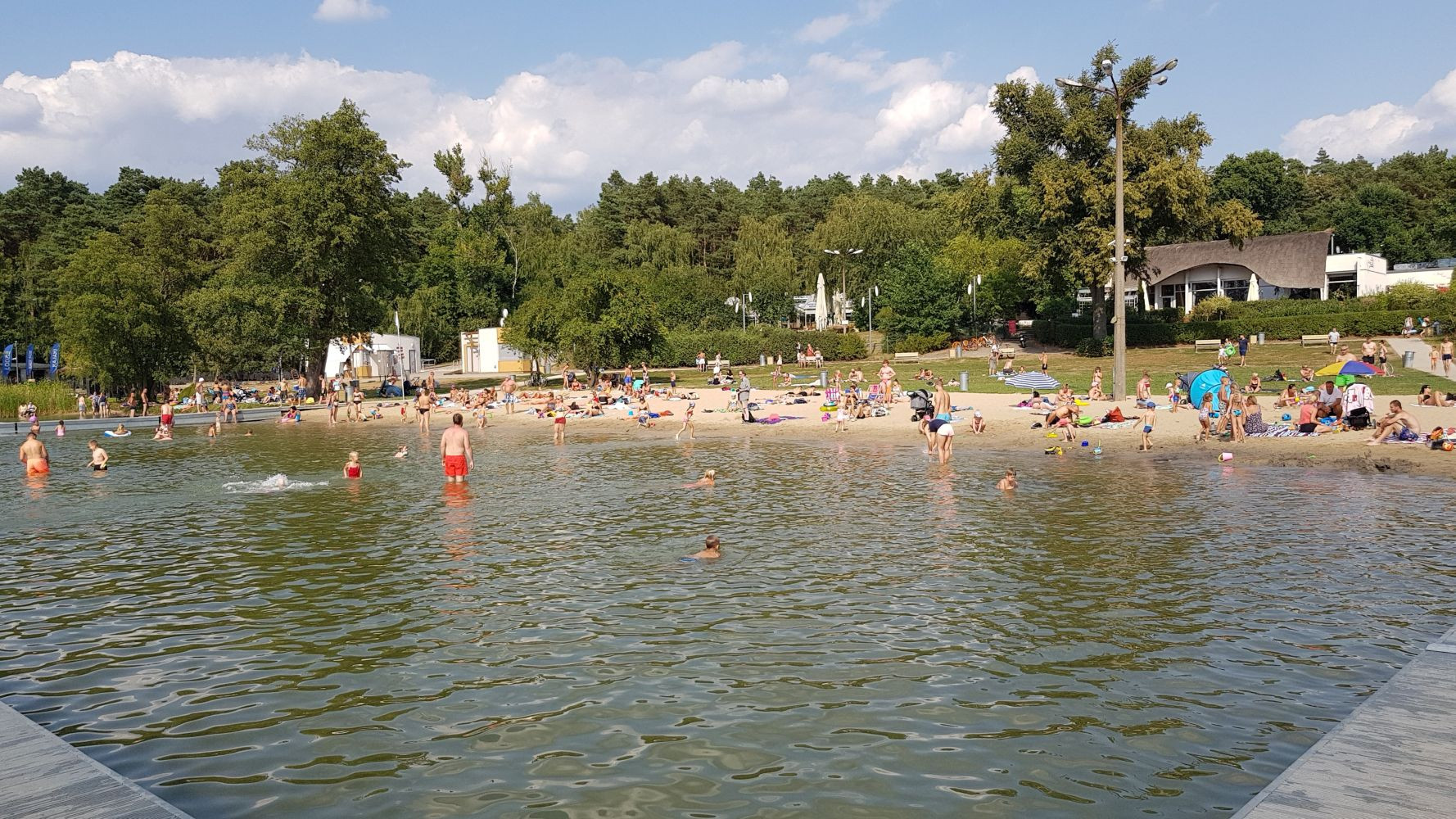 Zdjęcie przedstawia kąpielisko. Na plaży oraz w wodzie widać tłum ludzi. - grafika artykułu