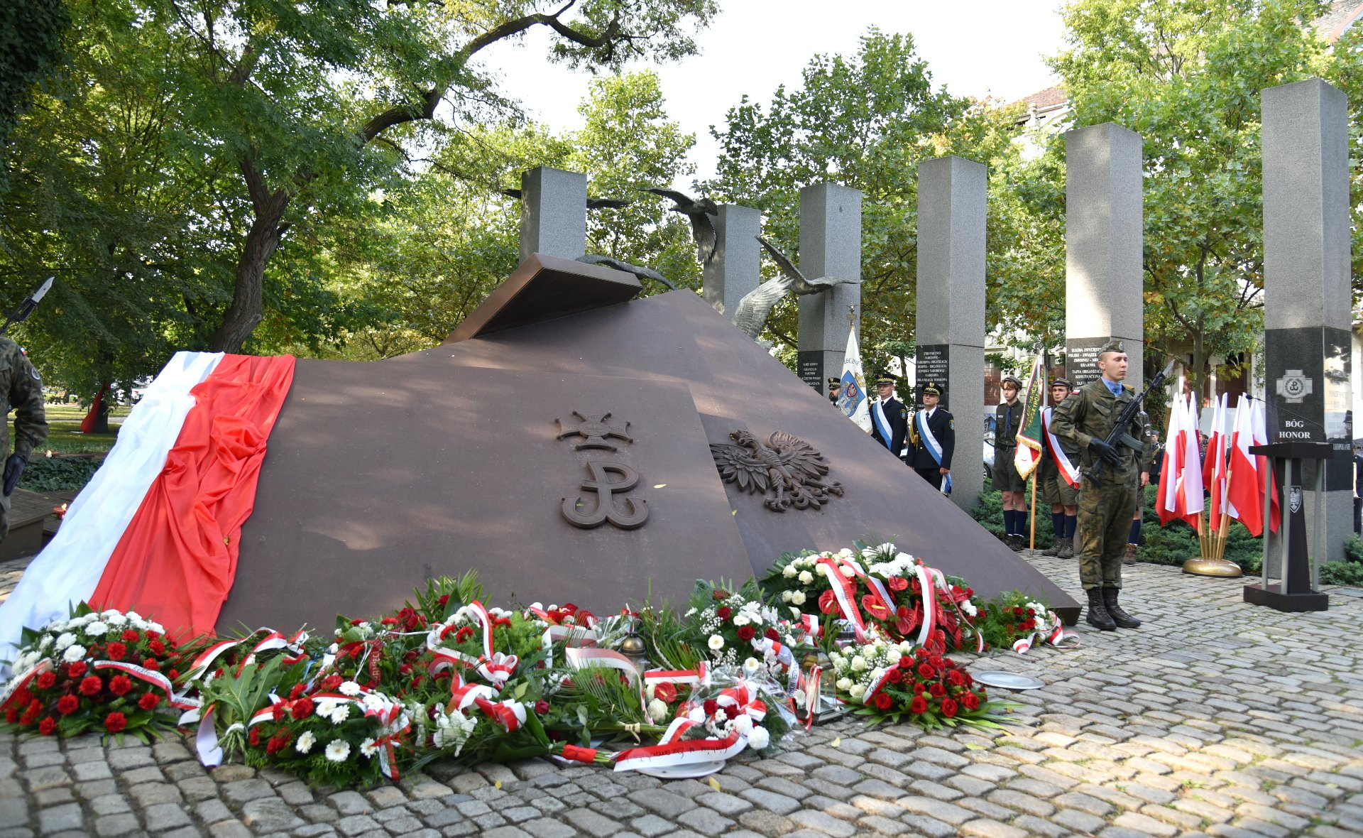 Zdjęcie przedstawia pomnik Polskiego Państwa Podziemnego. Pod nim leżą kwiaty. - grafika artykułu