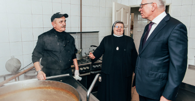 Na zdjęciu Jacek Jaśkowiak, obok siostra Józefa i kucharz, patrzą na ogromny gar pełen grochówki
