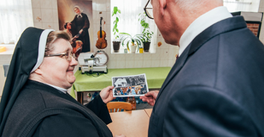 Na zdjęciu Jacek Jaśkowiak, prezydent Poznania, patrzy na zdjęcie, które trzyma w dłoni siostra Józefa