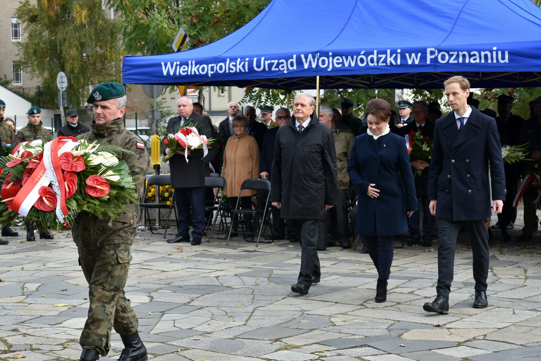 Na zdjęciu przedstawiciele władz miasta i województwa obok siebie, przed nimi żołnierz trzymający wiązankę kwiatów - grafika artykułu