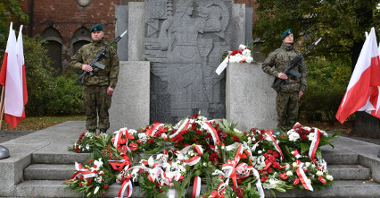 Na zdjęciu pomnik, obok niego żołnierze trzymający wartę honorową, pod pomnikiem złożone wiązanki