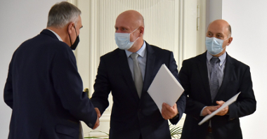 Na zdjęciu Bartosz Guss, zastępca prezydenta Poznania, ściska dłoń mężczyźnie odwróconemu tyłem do obiektywu, obok prezes Aquanetu