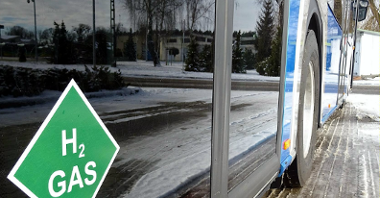 Na zdjęciu autobus wodorowy - zbliżenie na symbol wodoru na drzwiach