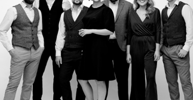 Czarno białe zdjęcie przedstawia grupę muzyków - kobiet i mężczyzn.