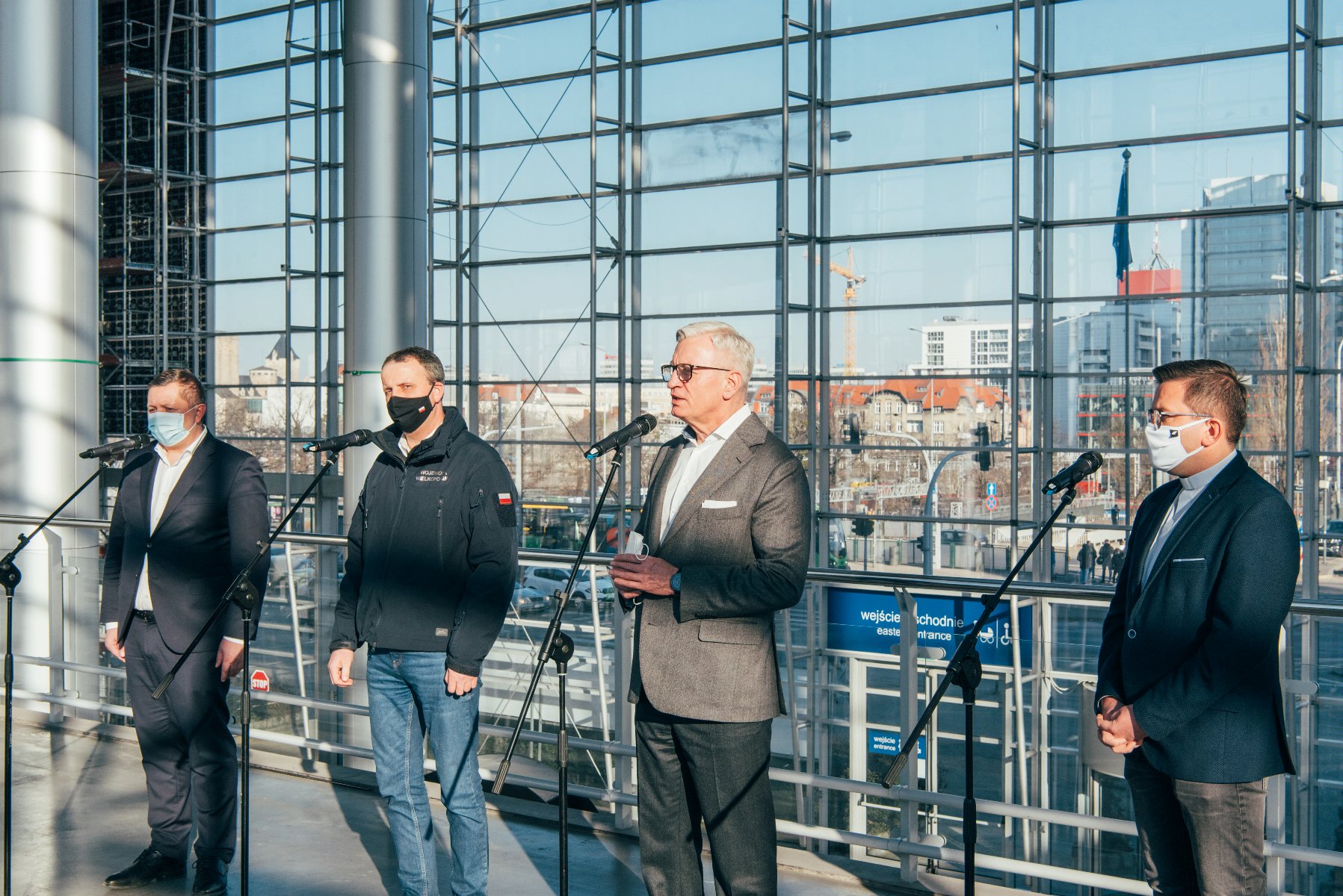 Czterej mężczyźni przed mikrofonami: prezydent Poznania, wojewoda wielkopolski, prezes Grupy MTP i dyrektor Caritas - grafika artykułu