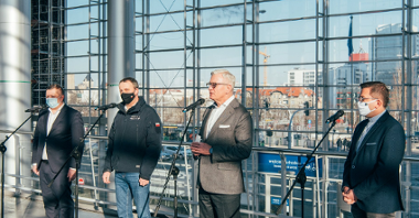 Czterej mężczyźni przed mikrofonami: prezydent Poznania, wojewoda wielkopolski, prezes Grupy MTP i dyrektor Caritas