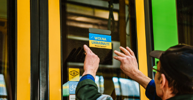 Niebiesko-żółta naklejka z napisem Wolna Ukraina po polsku i ukraińsku naklejona na drzwiach tramwaju