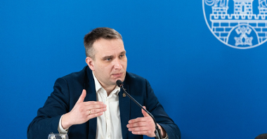 Na zdjęciu Mariusz Wiśniewski, zastępca prezydenta Poznania przy mikrofonie, za nim granatowa ścianka z herbem Miasta