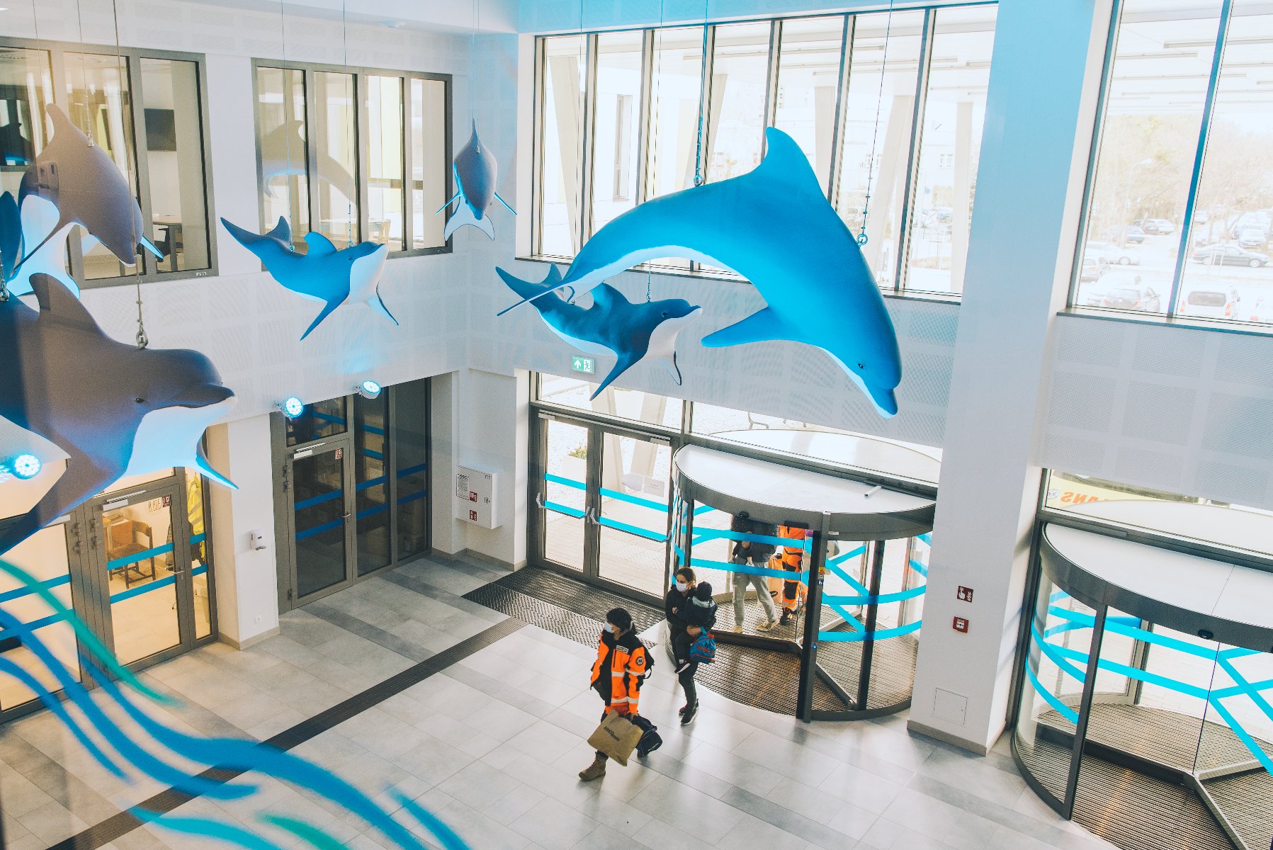 Na zdjęciu hol szpitala, pod sufitem podwieszane duże delfiny - grafika artykułu