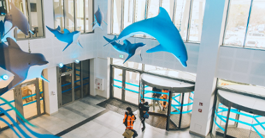 Na zdjęciu hol szpitala, pod sufitem podwieszane duże delfiny