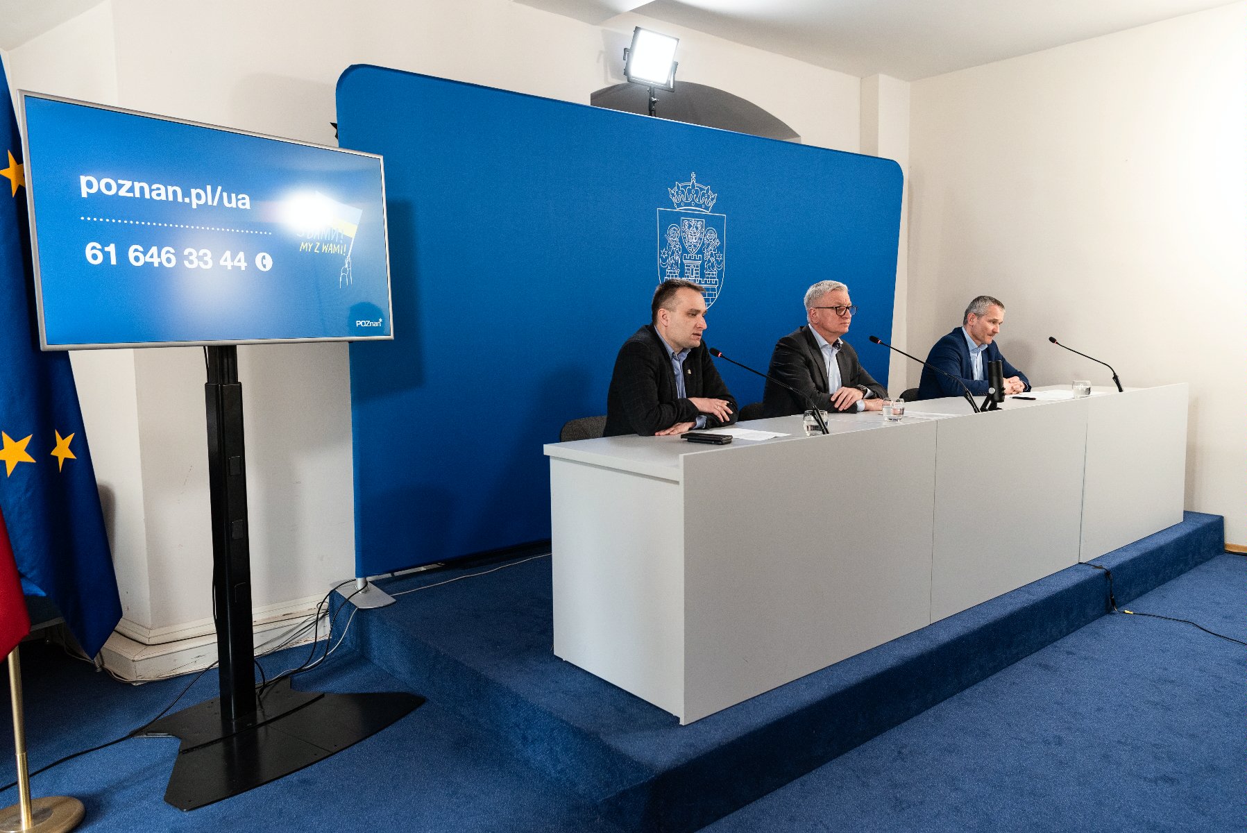 Wnętrze sali konferencyjnej, za stołem Jacek Jaśkowiak, prezydent Poznania i jego dwaj zastępcy, za nimi granatowa ścianka z herbem Miasta - grafika artykułu