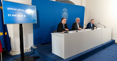 Wnętrze sali konferencyjnej, za stołem Jacek Jaśkowiak, prezydent Poznania i jego dwaj zastępcy, za nimi granatowa ścianka z herbem Miasta