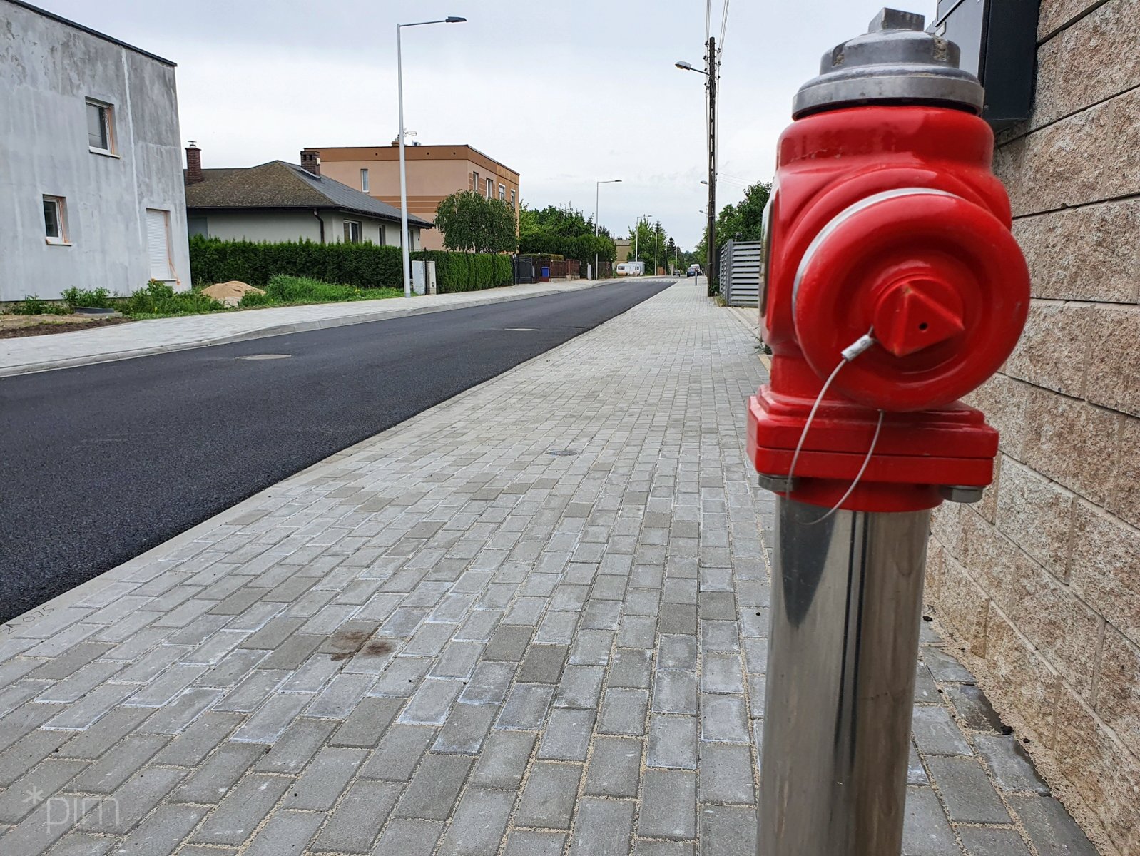 Na zdjęciu ulica z nowo położonym chodnikiem i nową nawierzchnią, na pierwszym planie czerwony hydrant - grafika artykułu