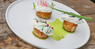 Na zdjęciu danie: kawałki ziemniaka, na nich twaróg i warzywa, podane na białym talerzu