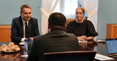 Na zdjęciu zastępca prezydenta Poznania i tłumaczka, rozmawiają z ambasadorem siedzącym tyłem do obiektywu