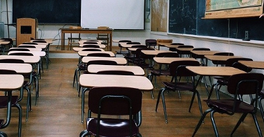 Na zdjęciu wnętrze klasy szkolnej, widać puste ławki i tablicę