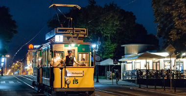 Na zdjęciu zabytkowy tramwaj po zmierzchu, oświetlony lampami