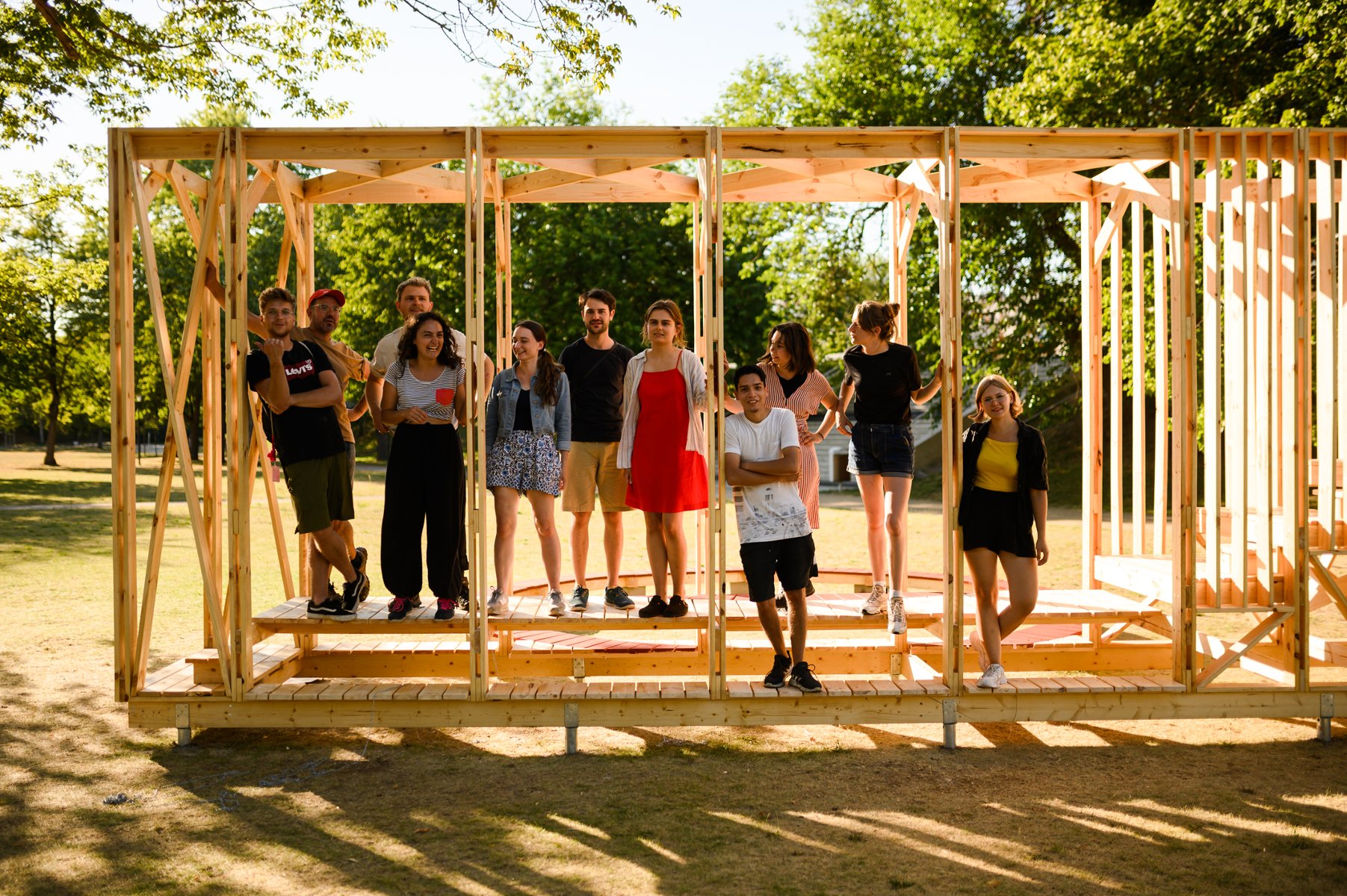 Na zdjęciu grupa ludzi stojąca w drewnianej konstrukcji w lesie - grafika artykułu