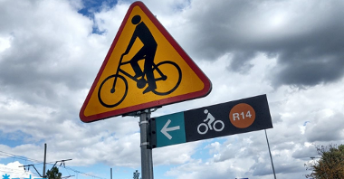 Znak drogowy a pod nim tabliczka z nowym oznakowaniem drogi rowerowej